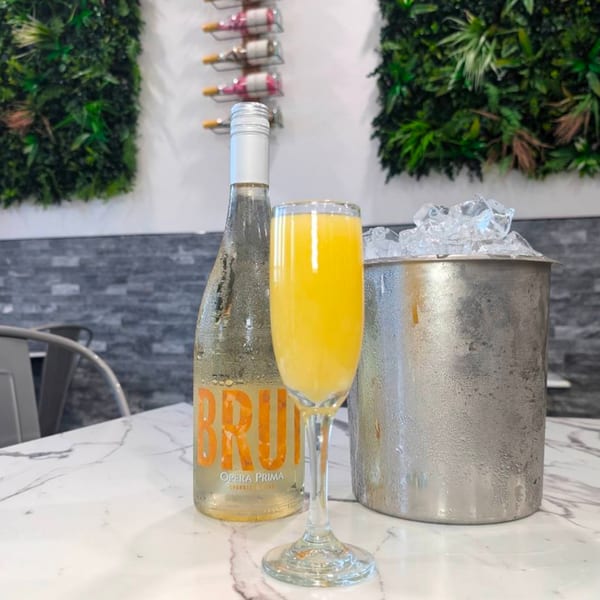 A mimosa, a bottle of Opera Prima Brut, and an ice bucket on a marble table.